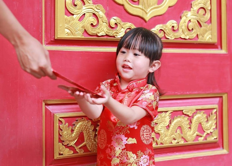 Người phụ nữ đưa phong bì màu đỏ cho một cô bé