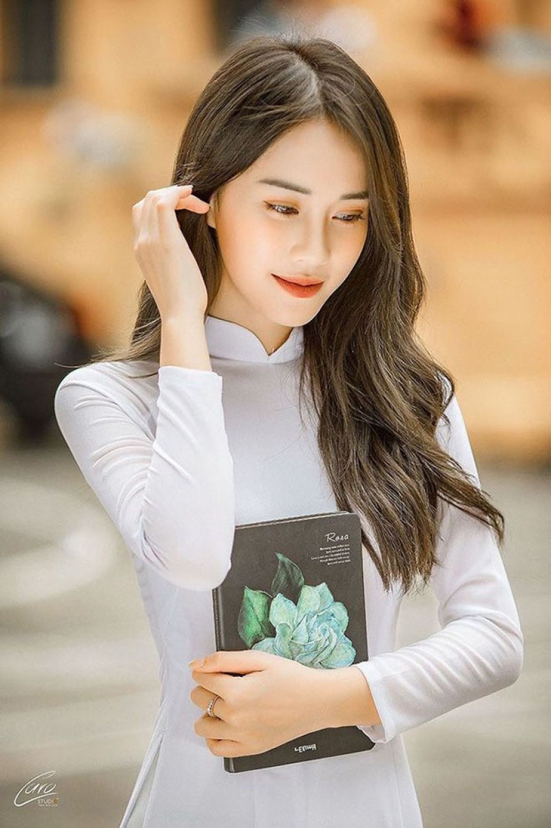 Đứng dưới hiên nhà hoặc nơi có không gian rộng, đưa tay vuốt nhẹ tóc, cười duyên dáng