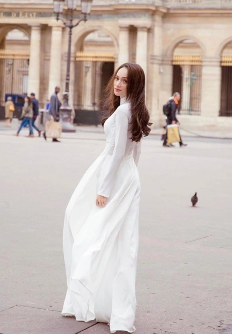 Đứng ngược hướng gió, lấy tay nhẹ nhàng tung tà áo dài lên, cười tươi.