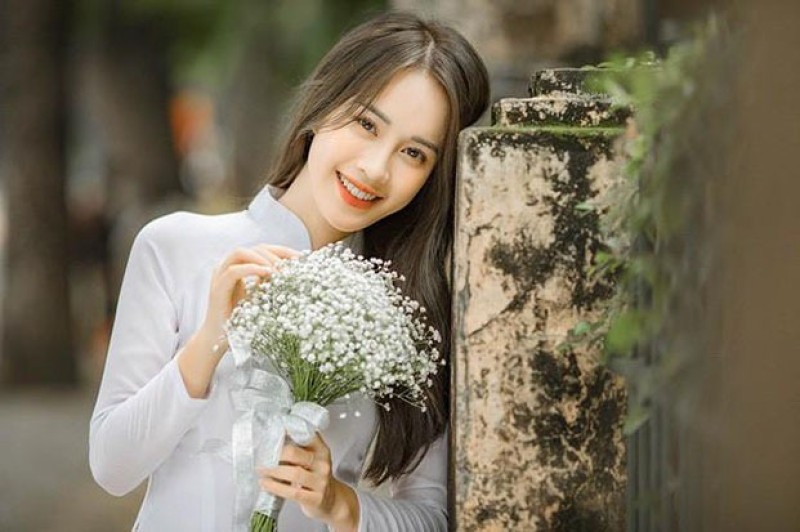 Ảnh chụp cận mặt nữ áo dài trắng với hoa